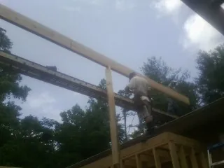 Carpenter setting a ridge beam over a new addition frame — Ice Dam Removal by Roofing Brothers in Valley Spring