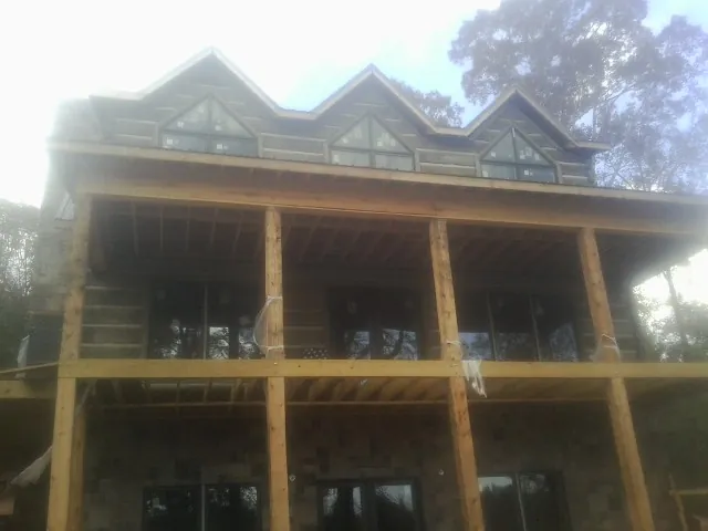 Dormers and porch framing on a large log home under construction — Roof Coating work by our crew in Valley Spring