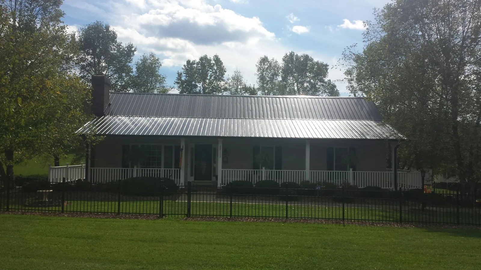 Gray metal roof on a brick ranch with a full width front porch — Gutter Guard Installation work by our crew in Valley Spring
