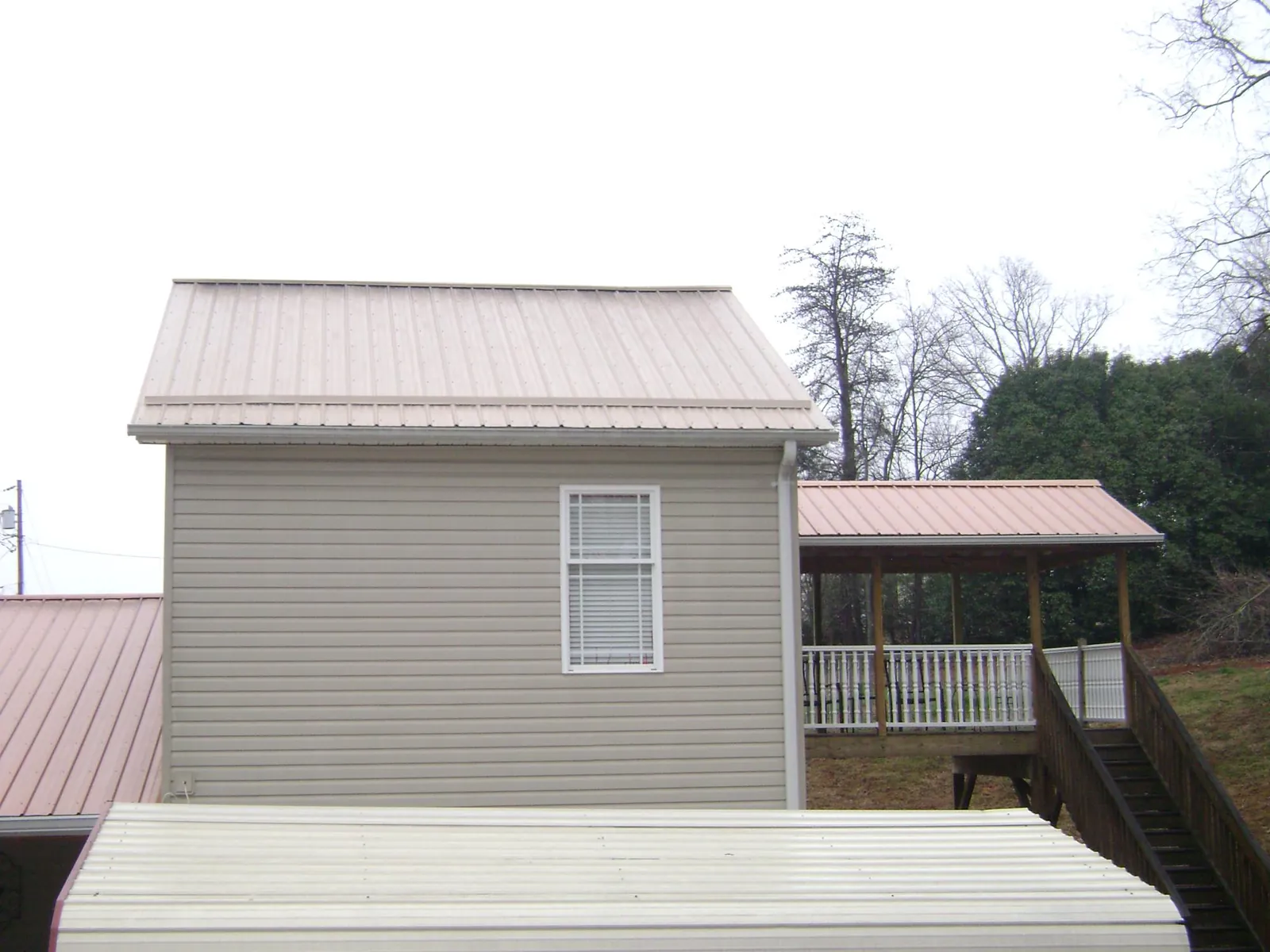 Tan metal roofs on a two story addition and attached porch, from a Roof Replacement job in Valley Spring