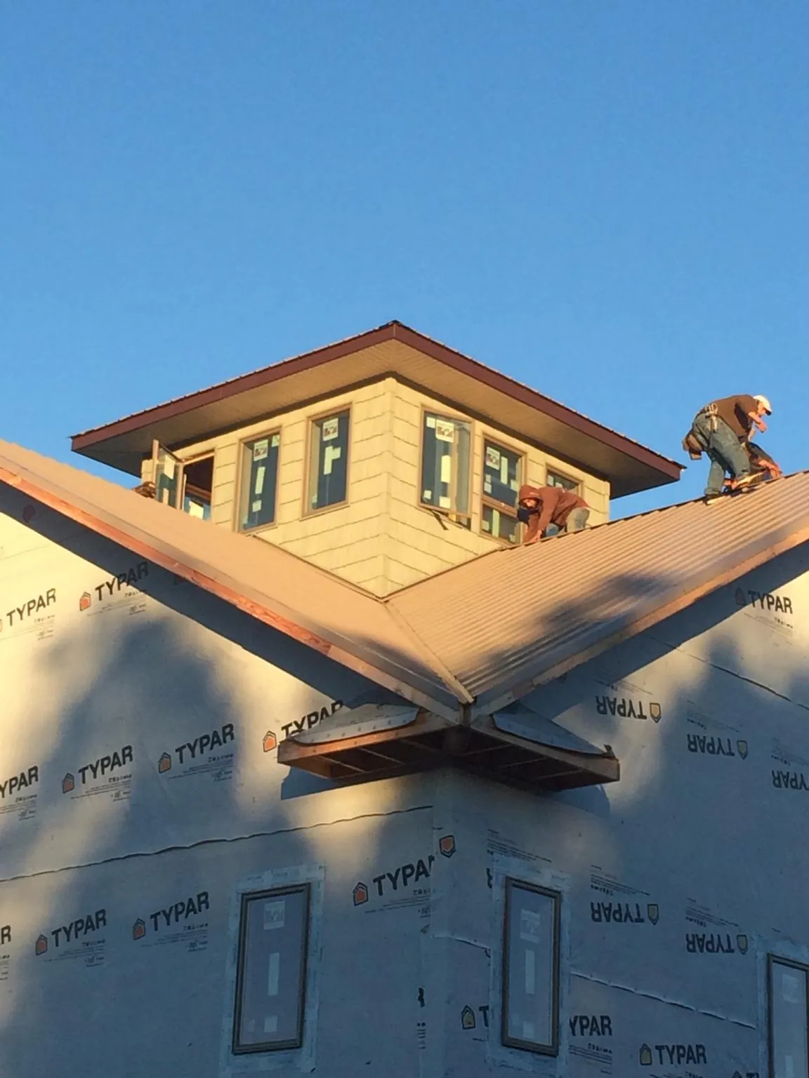Roofers working around a rooftop cupola on a new metal roof at sunset — Roof Waterproofing in Valley Spring by Roofing Brothers